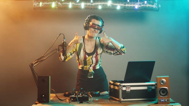 Disc jockey gives thumbs up while mixing music