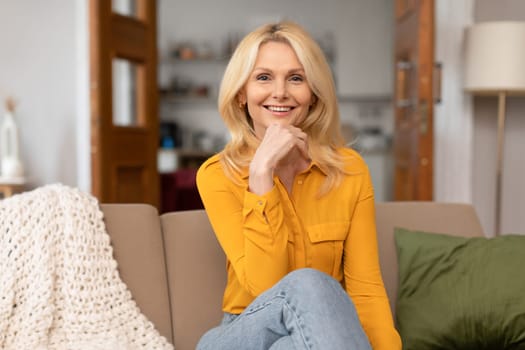 Portrait of middle aged blonde woman sitting on sofa indoor