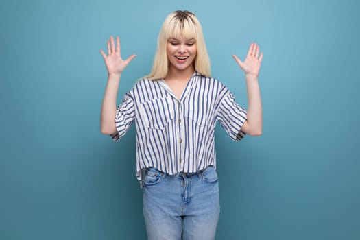surprised blond caucasian 20s woman in striped shirt on studio background with copy space