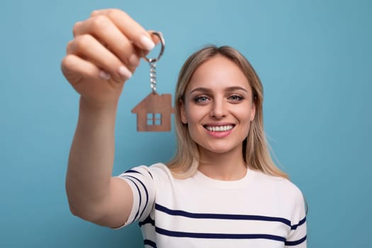 cute happy young woman is the owner of a new apartment on a blue isolated background