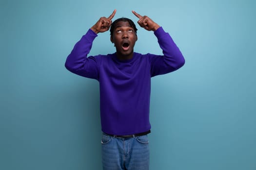 portrait of a brilliant smart dark-skinned american young guy in a blue hoodie and jeans isolated on a solid background