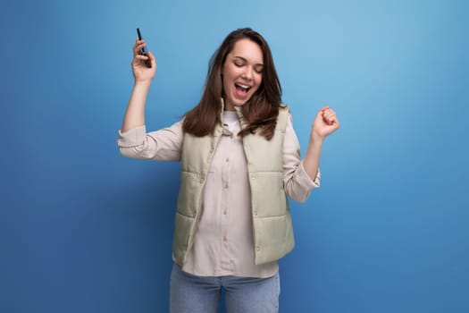 energetic young brunette woman in casual clothes holding her new gadget phone in her hands
