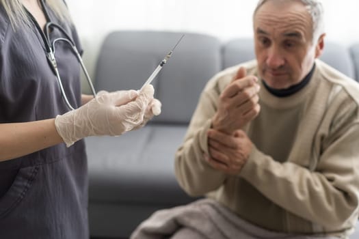 Doctor giving vaccination shot to elderly patient by syringe or injunction at home. concept of home health check to seniors during coronavirus covid-19 pandemic