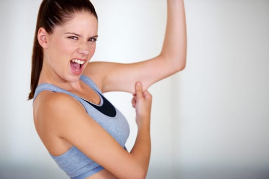 Fitness, arm and woman holding her fat for health, wellness and weight loss goals in a studio. Shout, scream and portrait of young female person showing bicep body for exercise or workout motivation