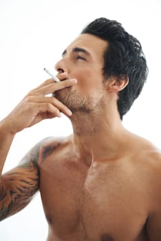 Man, cigarette and smoking for addiction or drag of tobacco against a white studio background. Face of handsome or attractive male person, model or smoker addict in relax and enjoying stress relief