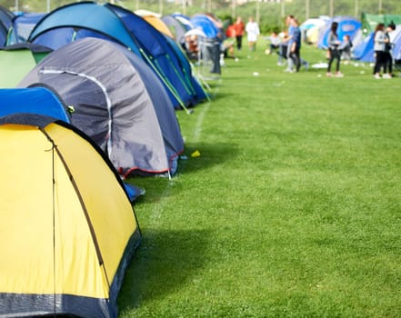 Music festival, camping and tents in park with people in summer, holiday or field at concert in countryside. Camp, site or adventure shelter on grass in woods or group at carnival in morning of rave