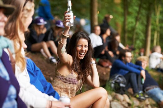 Alcohol, outdoor music festival and excited woman, crowd and celebrate in forest, nature or woods for social event. Cheers, drinks and audience girl energy, celebration and listen to park performance