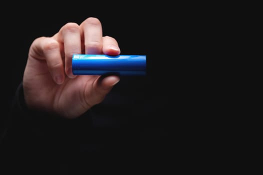 Lithium-ion battery for power in a human hand, on a black background. Woman's hand showing a battery, close-up, mockup