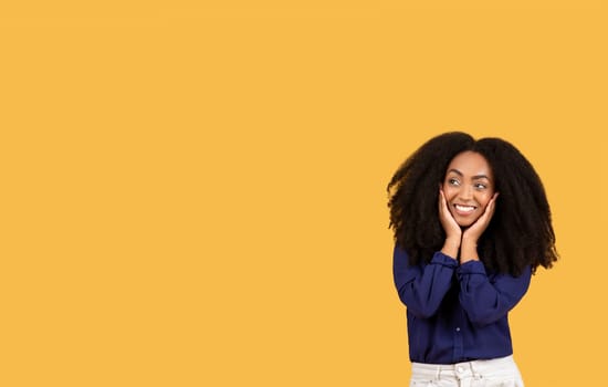 Joyful young black woman with curly hair smiling on a yellow background