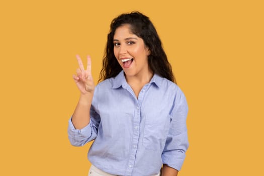 Glad latin millennial brunette lady in casual show peace sign with hand, enjoy lifestyle