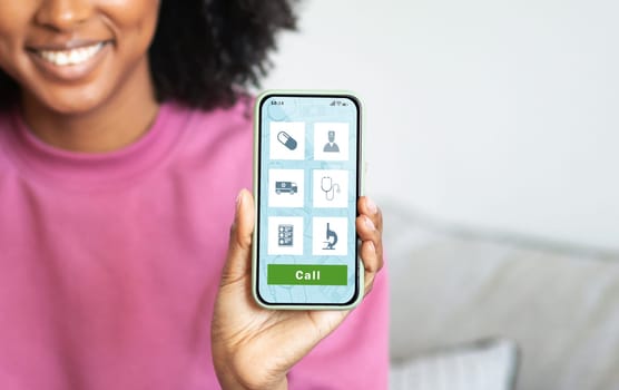 Smiling black woman demonstrating healthcare app opened on her smartphone