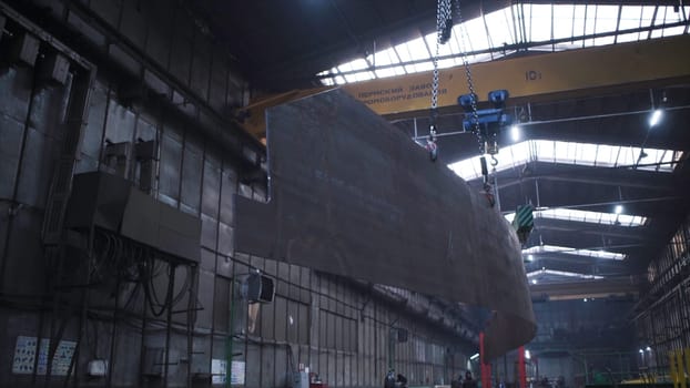 Metal frame hanging on chains in factory. Clip. Large metal panel suspended on chain in factory warehouse. Transfer of metal panels on circuits in plant