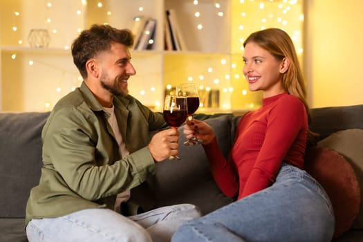 Happy couple toasting with wine glasses in a cozy room
