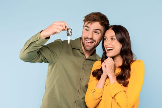 Excited couple with new car key, joyous purchase celebration