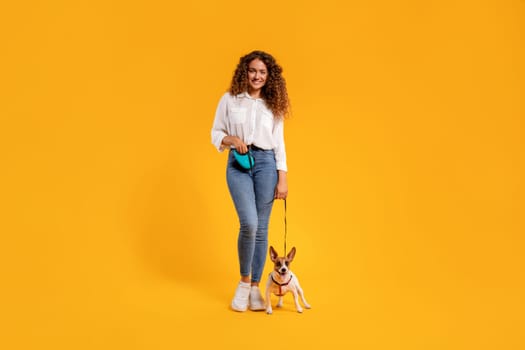 Woman with dog on leash against yellow wall