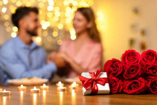 Man surprises partner with gift and roses during romantic candlelit dinner