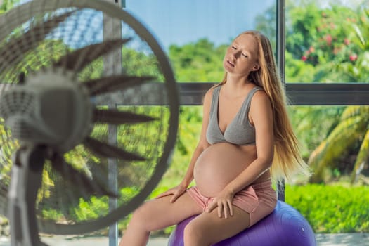 A pregnant woman seeks relief from an abnormal heatwave by using a fan, ensuring her comfort and well-being during sweltering conditions