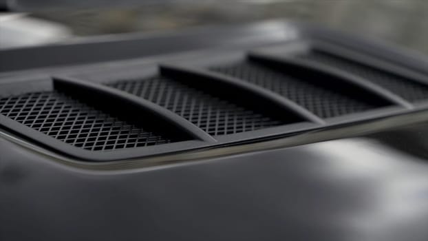 Close up for detail of air vents on the bonnet of a modern black car. Stock. Car exterior background detail of air intake in hood, design concept.