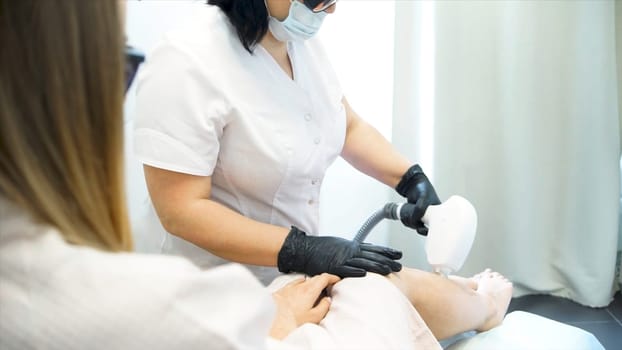 Close-up Of A Beautician Waxing Womans Leg In Beauty Spa. Process depilation female legs and hands in a beauty salon. Close up waxing in by a beautician in a spa center