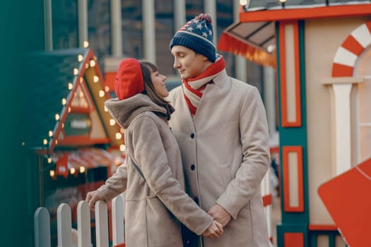 Adoring couple gazing into each other's eyes at a lively Christmas fair
