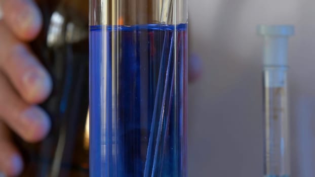 Scientist Pours Blue Pattern Chemicals Into In Flask. health care and medical concept. Scientist are certain activities on experimental science like mixing chemicals