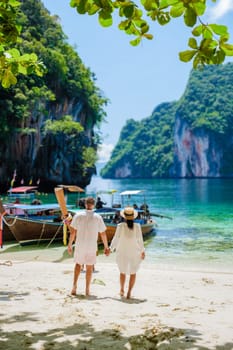 Koh Lao Lading near Koh Hong Krabi Thailand, beautiful beach with longtail boats, a couple of European men, and an Asian woman on the beach. Couple on a boat trip