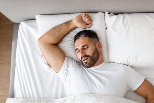 man in casual clothing lies asleep resting in modern bedroom