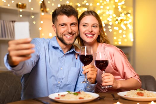 Happy couple taking selfie with wine during dinner