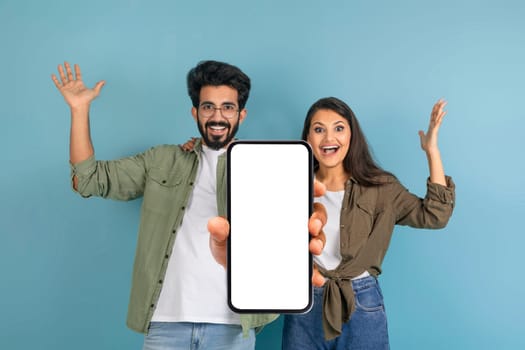 Happy young indian couple showing big cell phone, mockup