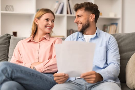 Happy young european spouses checking documents at home