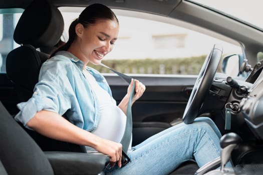pregnant woman in car adjusting seat belt for safety inside