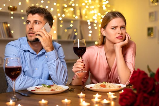 Distracted man on phone, woman upset at romantic dinner