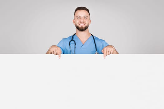 Happy male nurse pointing at a blank banner for text