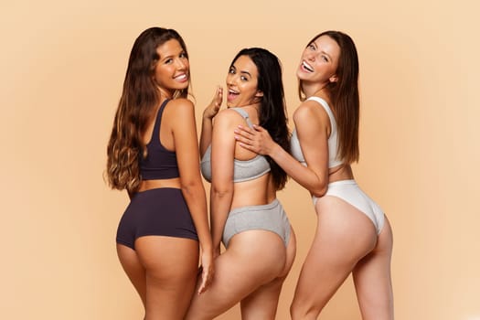 Three multiracial young women in stylish activewear smiling and posing playfully