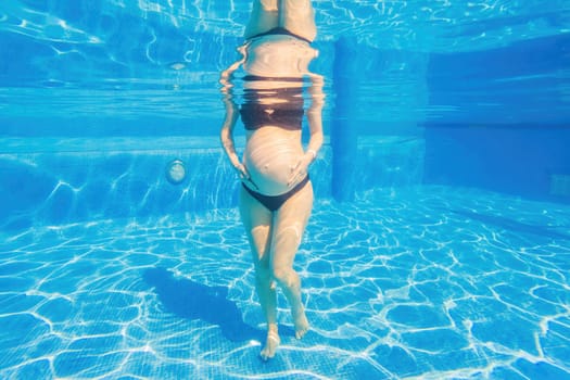 Pregnancy embraced underwater a tranquil scene as a woman tenderly hugs her belly in the pool, capturing the beauty of maternal connection