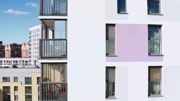 Panoramic view of facade of residential building. Stock footage. View of windows of modern apartment building on sunny day. Beautiful facade with windows of residential building in modern complex