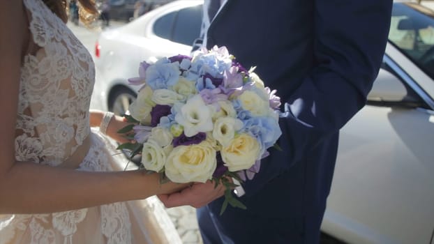 Bride and groom holding colourful wedding bouquet. Marriage concept. Beautiful young wedding couple outside in nature. Wedding couple with the stylish bouquet
