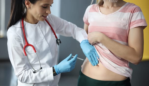 Doctor making injection of insulin into abdomen of female patient