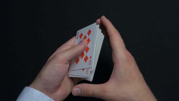 Poker game - shuffling cards. Man's hands shuffing cards. Close up. Man's hands shuffling playing cards. Dealer's hands shuffling cards during a poker game