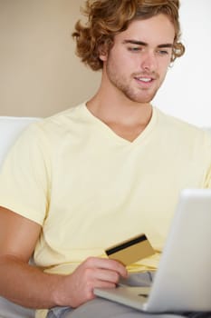 Young man, credit card and laptop for online shopping, fintech payment and digital money in trading or stock market. Online user, trader or person on his computer for internet banking or cash on sofa