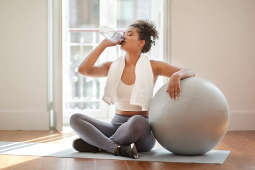 lady drinking water having hydration break during workout at home