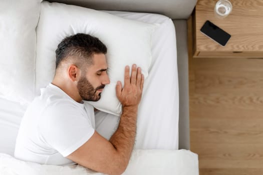 Man enjoys healthy sleep routine lying in modern bedroom