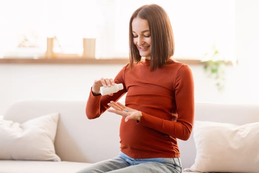Young pregnant woman taking vitamins pills sitting in living room