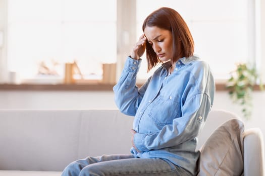pregnant woman feeling unwell suffering from headache at home