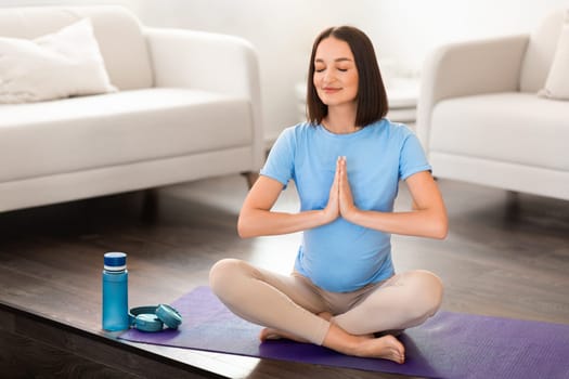 Calm pregnant lady practices pilates and yoga meditating at home