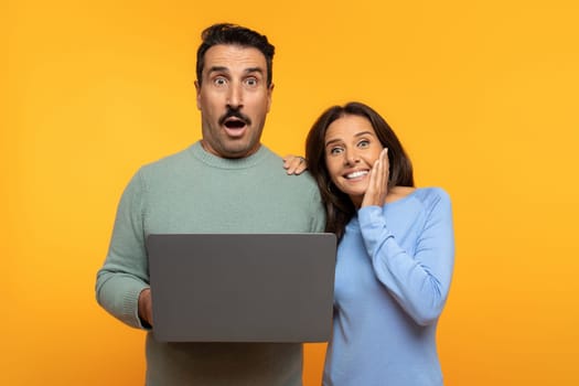Shocked european senior man and woman exhibit excited expressions looking at laptop screen