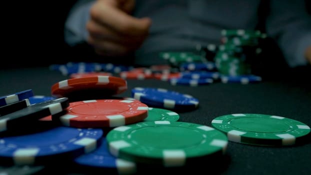 Throw the blue chips in poker. Blue and Red Playing Poker Chips in Reflective black Background. Closeup of poker chips in stacks on green felt card table surface in slow motion
