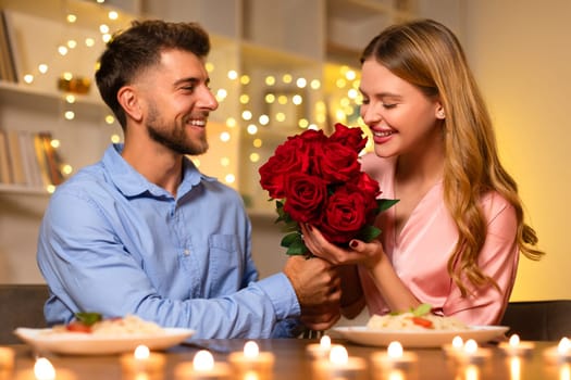 Man giving woman a bouquet of roses during a romantic dinner
