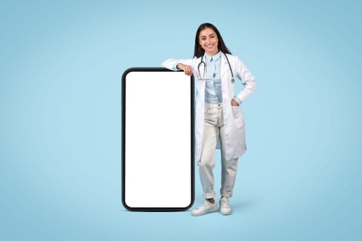 Friendly woman doctor leaning on a blank mobile screen