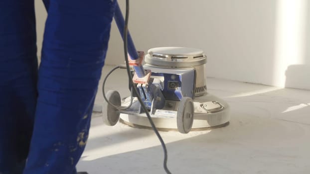 Man polishing marble floor in modern office building. Man works with grinding machine for floor